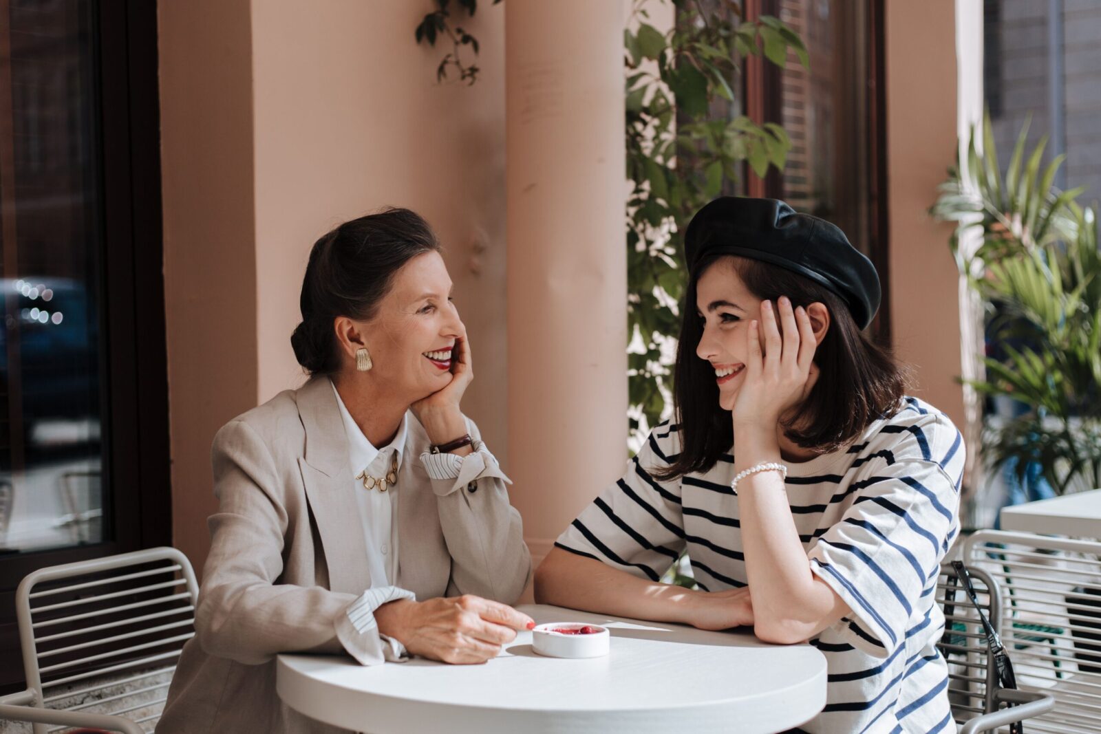 A stylish grandmother and granddaughter sharing a joyful moment at an outdoor cafe.